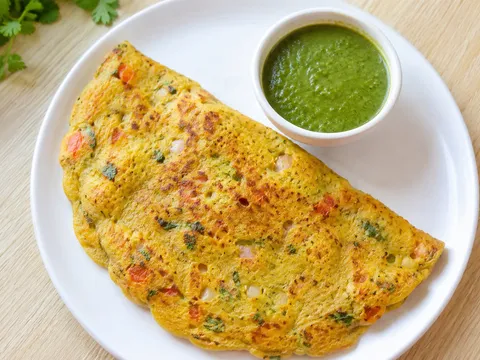 A folded besan chilla with chopped vegetables on a plate