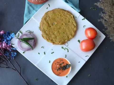 Two moong dal chillas on a plate with a side of curd
