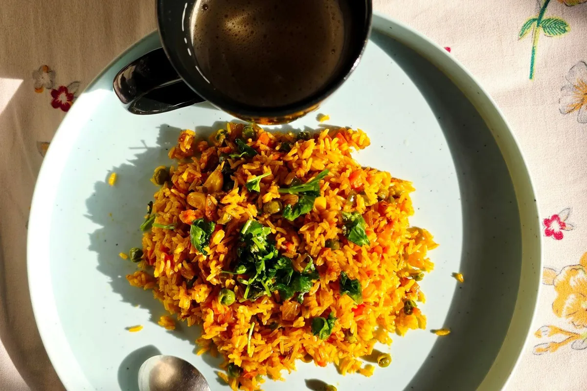 A plate of vegetable poha garnished with coriander and lemon